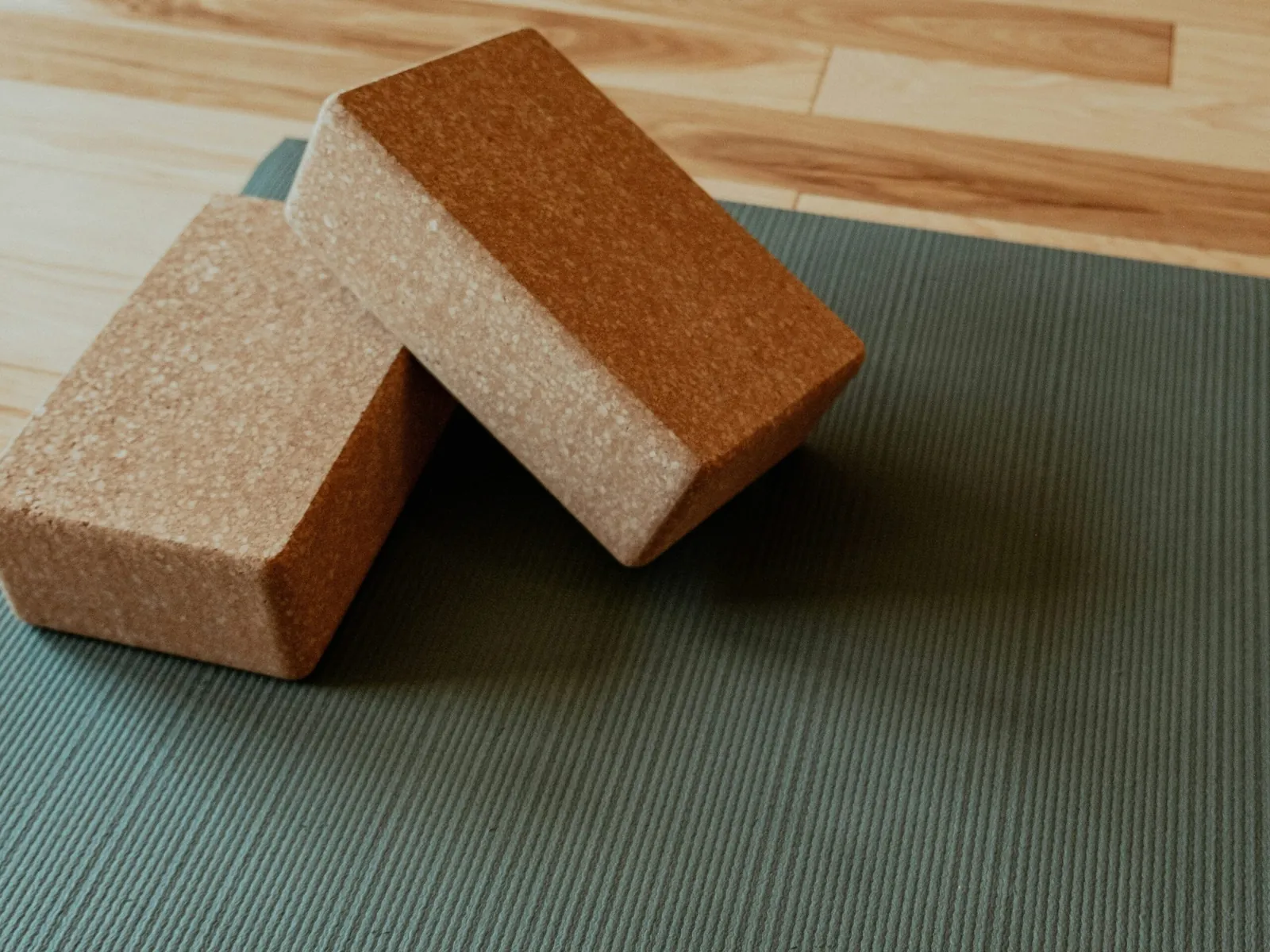 Two cork yoga blocks on a green mat.